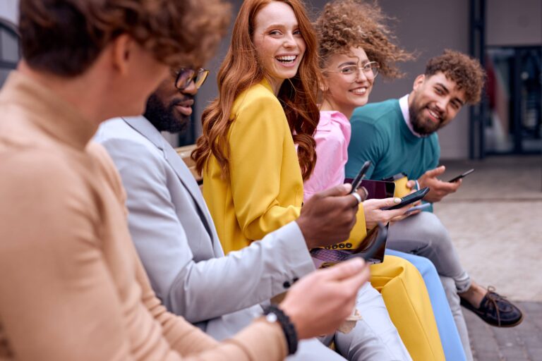young diverse coworkers during break time outside of office, sitting on bench having fun