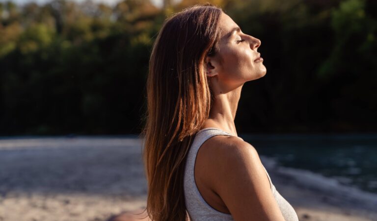 Young woman with long hair enjoying sun with closed eyes